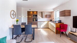 A modern kitchen with built-in appliances, a dining area with a table and chairs, and a red chair.