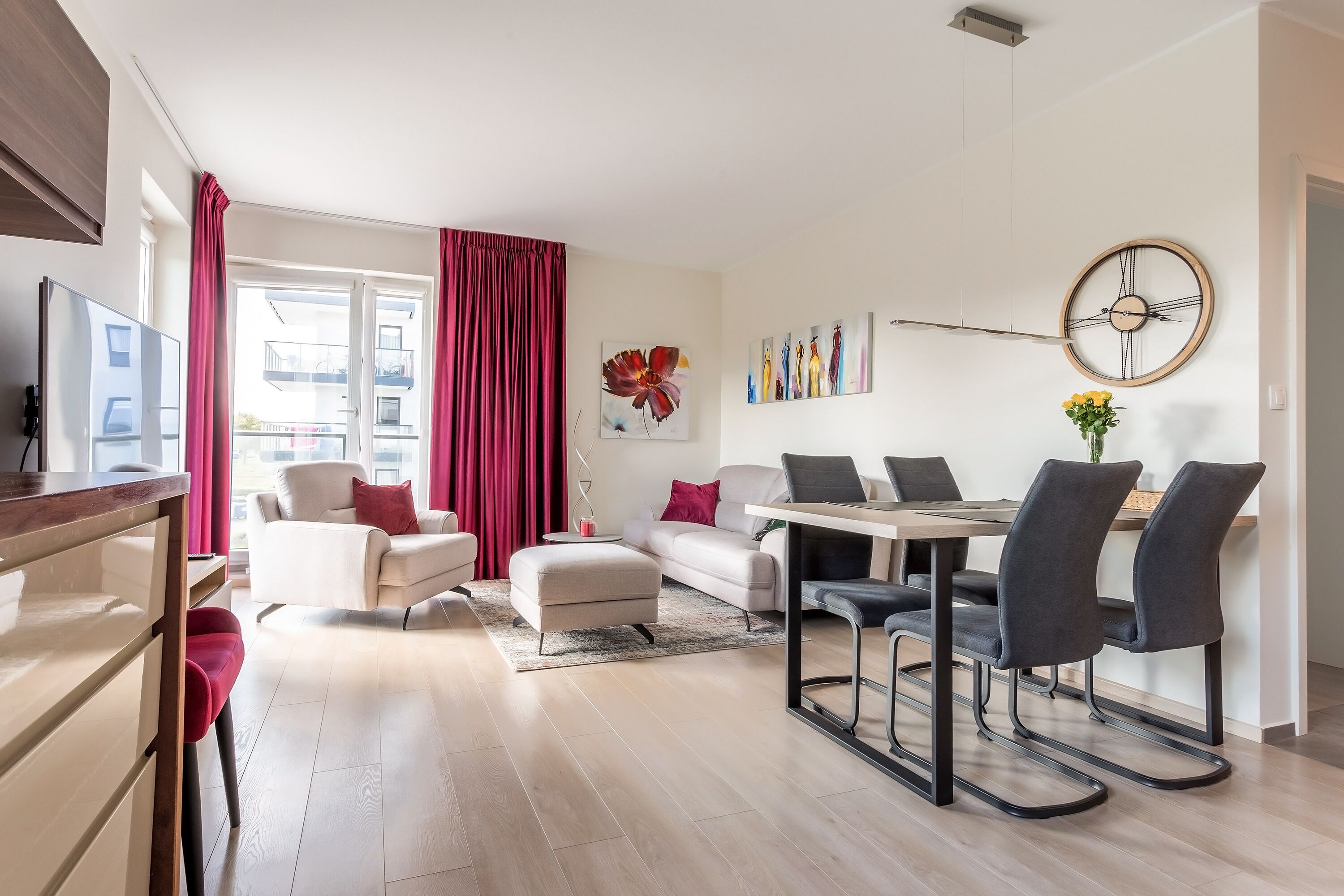 A modern living room with a dining area, featuring a sofa, ottoman, and a dining table with chairs.