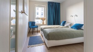 A bedroom with a bed, a chair, a window, and a lamp.