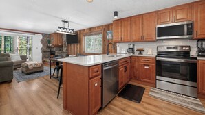 A kitchen with wooden cabinets, stainless steel appliances, a stone accent wall, and a view of the outdoors. - Beaver Village Unit #1514 Family friendly 2 bedroom cabin themed interior (Winter Park)