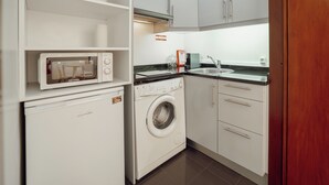 Una cocina compacta con microondas, lavadora y lavaplatos.