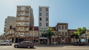 Vista de la calle con edificios de varios pisos, un semáforo y automóviles estacionados.