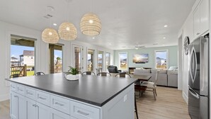 A modern kitchen with a large island, white cabinetry, and pendant lighting.