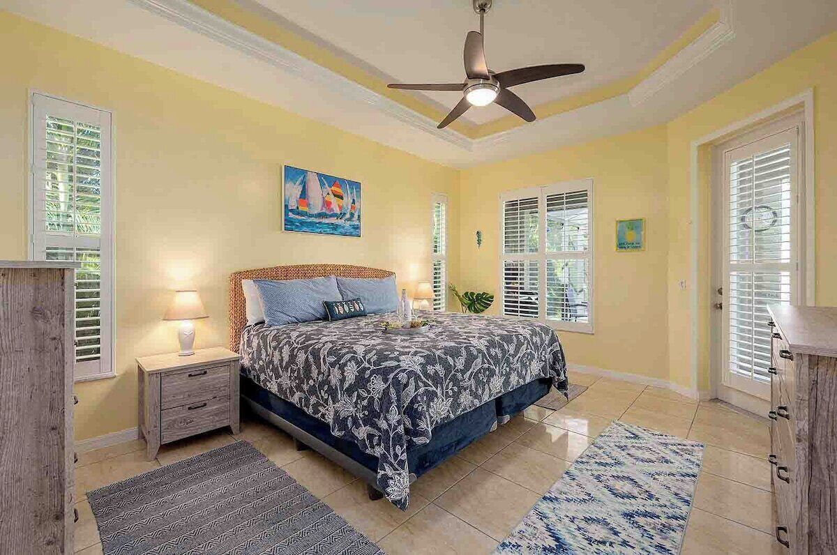 A bedroom with a bed, nightstands, a ceiling fan, and a window with blinds.