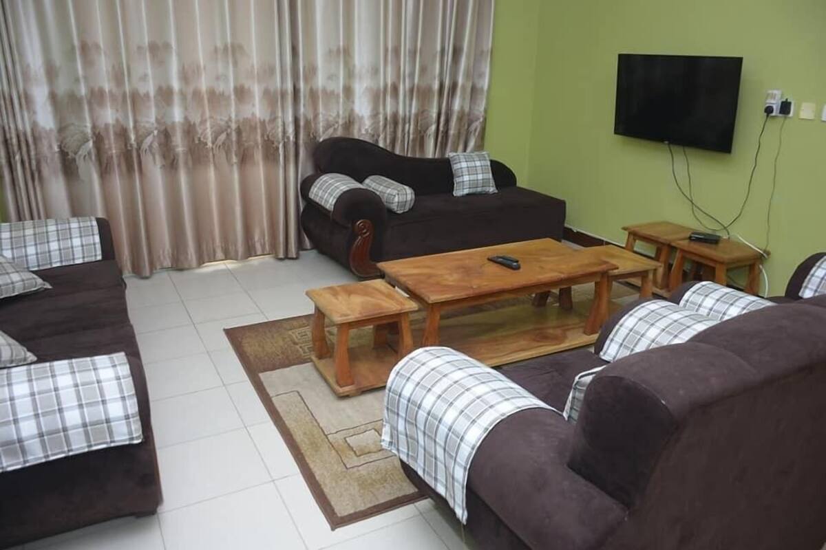 A living room with a sofa, a coffee table, and a television mounted on the wall.