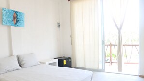 A bedroom with a bed, a small bedside table, a power outlet, and a window with curtains. - Queen size Superior basic Room (Zihuatanejo)