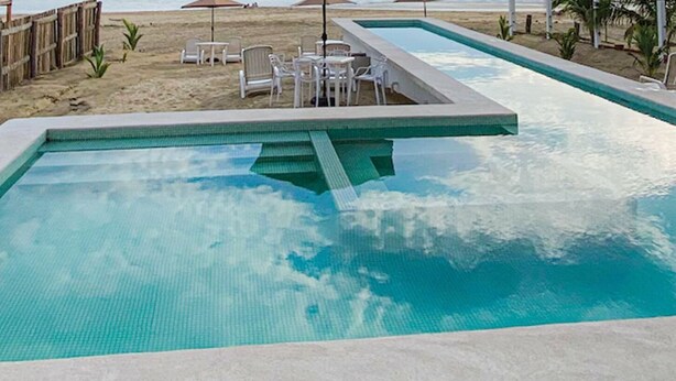 A swimming pool with a tiled deck, surrounded by lounge chairs and tables. - Queen size Superior basic Room (Zihuatanejo)