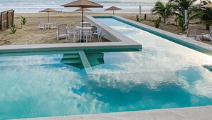 Une piscine dotée d’une terrasse carrelée, entourée de chaises longues et de tables.