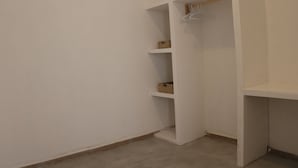 Un armario blanco con estantes abiertos y una barra para colgar.