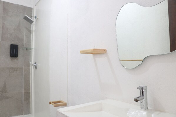 A bathroom with a shower, a sink, a mirror, and a soap dish.