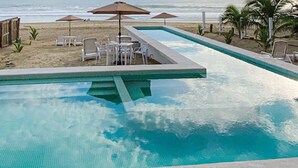 Une piscine dotée d’une terrasse carrelée, entourée de chaises longues et de tables.