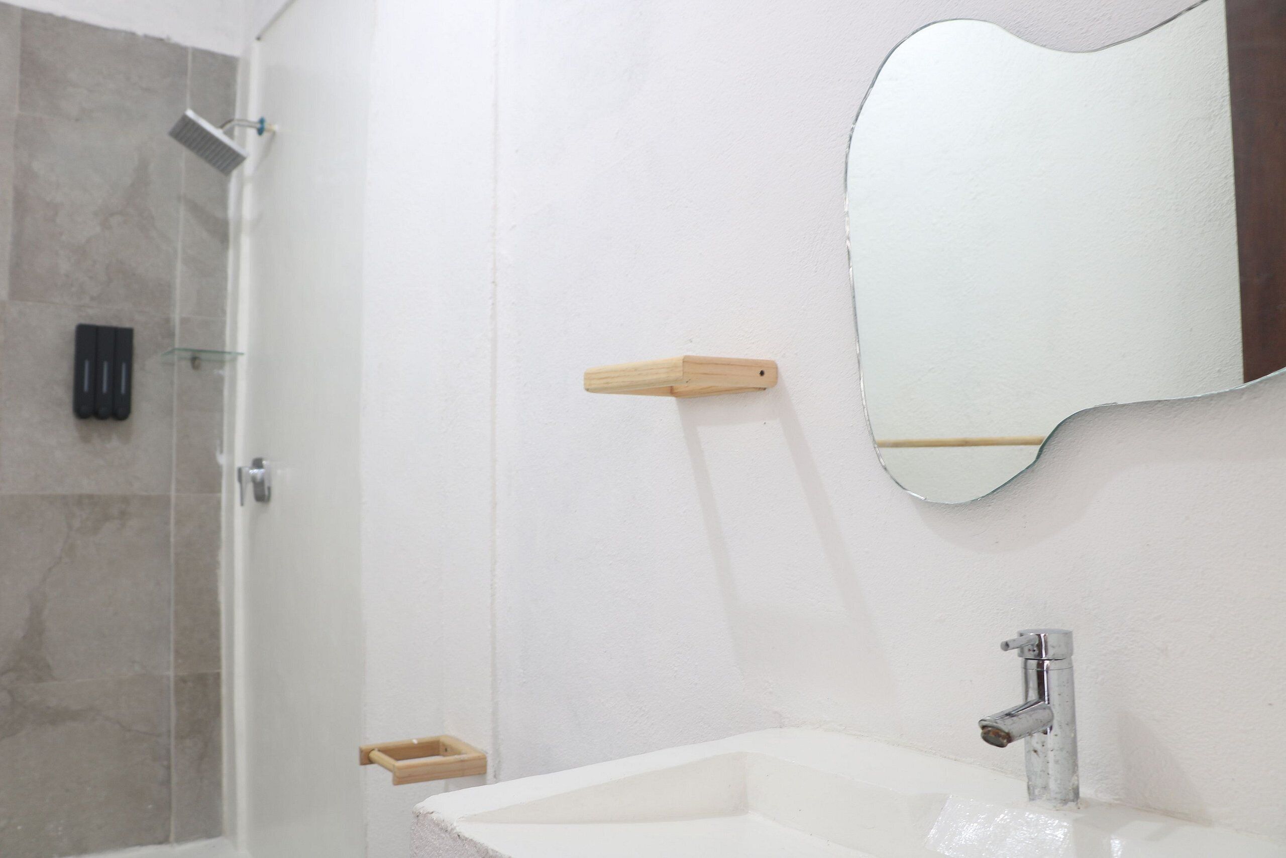 A bathroom with a shower, a sink, a mirror, and a soap dish.