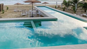 Una piscina amb un solàrium enrajolat, envoltada de gandules i taules.