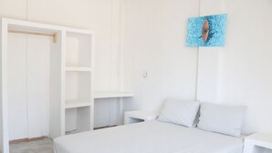 Un dormitori amb llit, un armari blanc, una nitòria i un quadre penjat a la paret.