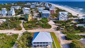 An aerial view of a coastal residential area with houses, a beach, and a swimming pool with lounge chairs. - Gulf View Getaway w/Pool and Fire Pit (Port St. Joe)