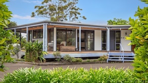 A modern house with a covered porch, large windows, and a garden area. - Hidden Orchard - Pet Friendly - 4 Mins Walk to Beach (Callala Bay)