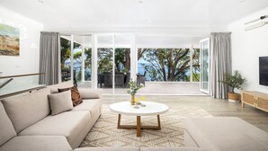 Ein modernes Wohnzimmer mit einer Couch, einem Couchtisch und Blick ins Freie.
