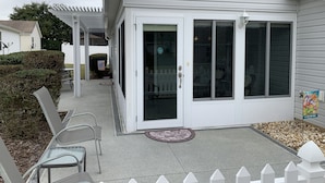 A white building with a covered patio area, a white picket fence, and a welcome sign. - Central Location!! Beautiful Villa with 2 Seater Gas Golf Cart & WIFI (The Villages)