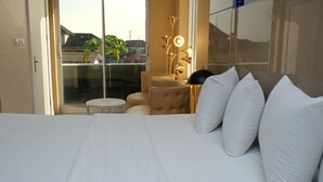 A hotel room with a large bed, a seating area with a small round table, and a view through a glass door. - A boutique hotel, situated in the middle of Nigeria's commercial capital Lagos. (Lagos)