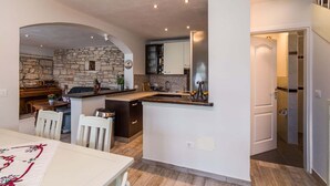 Una cocina moderna con pared de piedra, mesa de comedor de madera e isla integrada.