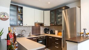 Una cocina moderna con armarios de madera oscura, un refrigerador de acero inoxidable, una cafetera y un reloj en la pared.