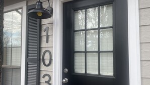 A black front door with a glass panel and a number "103" on the wall beside it.