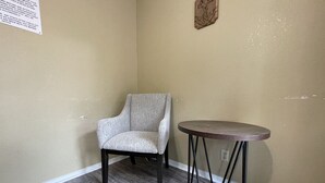 A room with a grey upholstered armchair and a round table with a metal base.