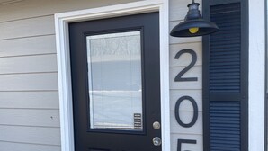 A black door with a window and a number '205' on the wall beside it.