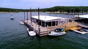 Un port de plaisance avec des bateaux amarrés, un bâtiment portant une enseigne et une jetée s’avançant dans l’eau.