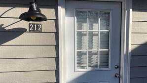 A white door with a window, a number '212' sign, and a hanging light fixture.