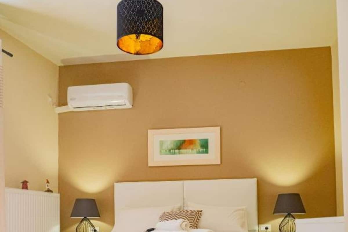 A bedroom with a bed, two bedside tables with lamps, a framed picture on the wall, and a radiator.
