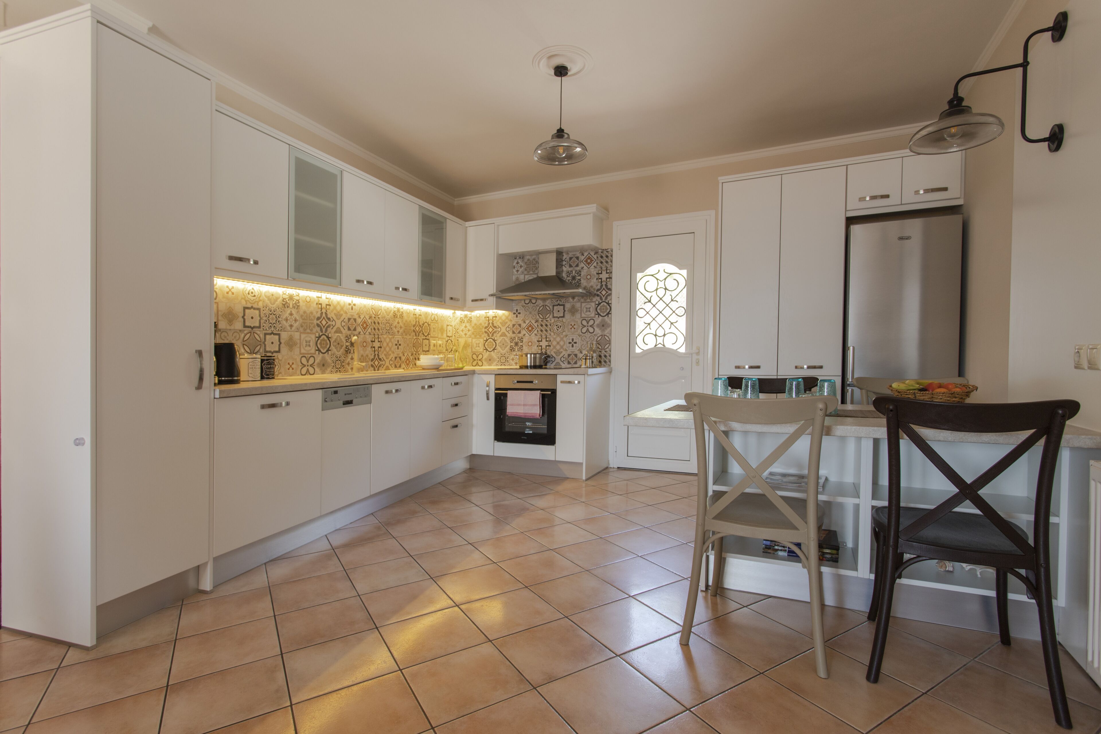 Una cocina moderna con armarios blancos, un refrigerador de acero inoxidable y salpicadero de azulejos.
