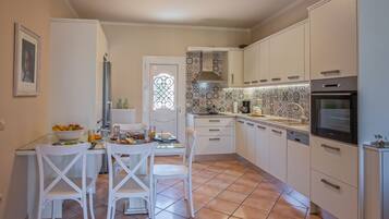 A kitchen with white cabinets, a tiled backsplash, and a dining area with a table and chairs.