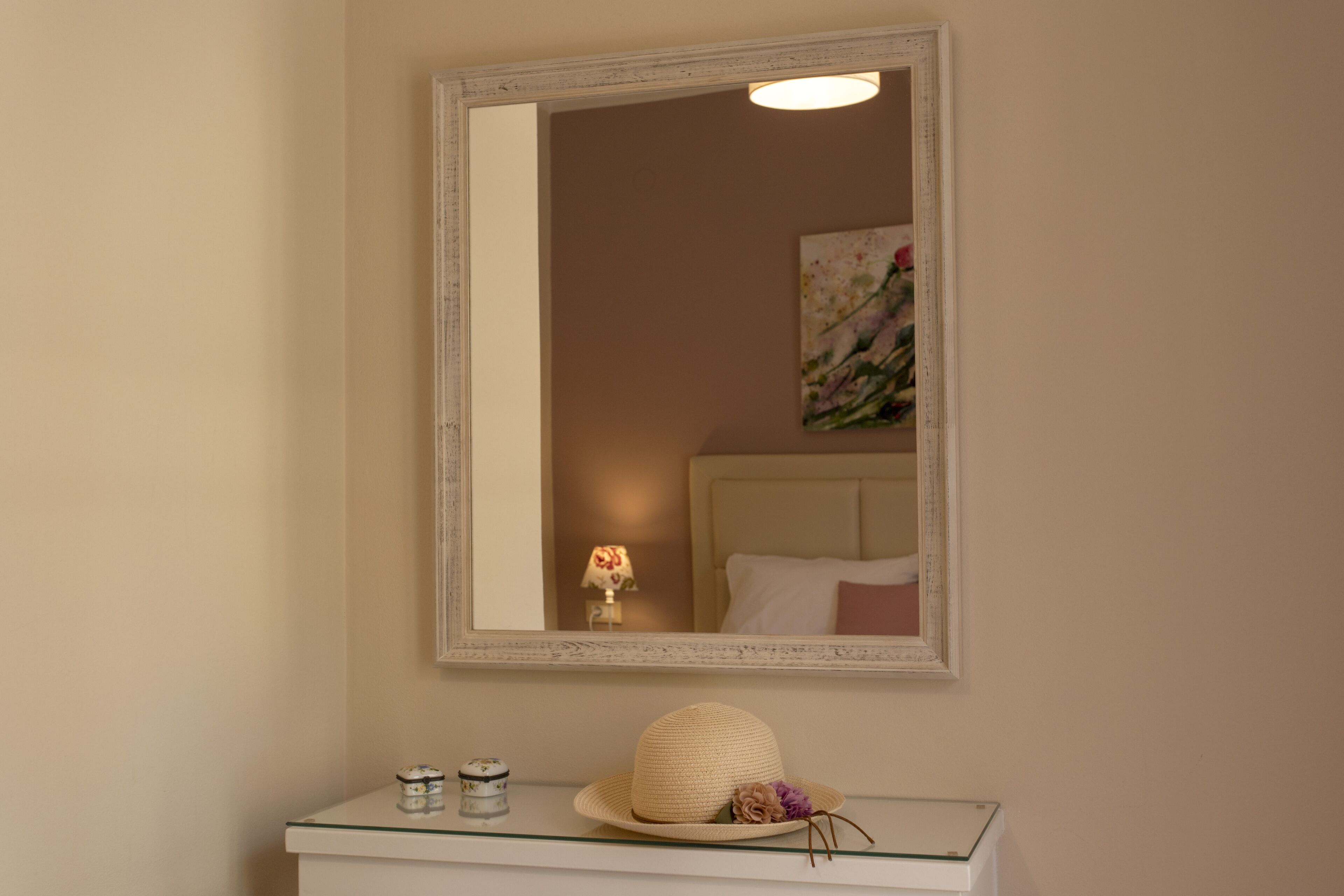 Een badkamer met een grote spiegel, een witte wastafel en een decoratieve hoed op het aanrecht.