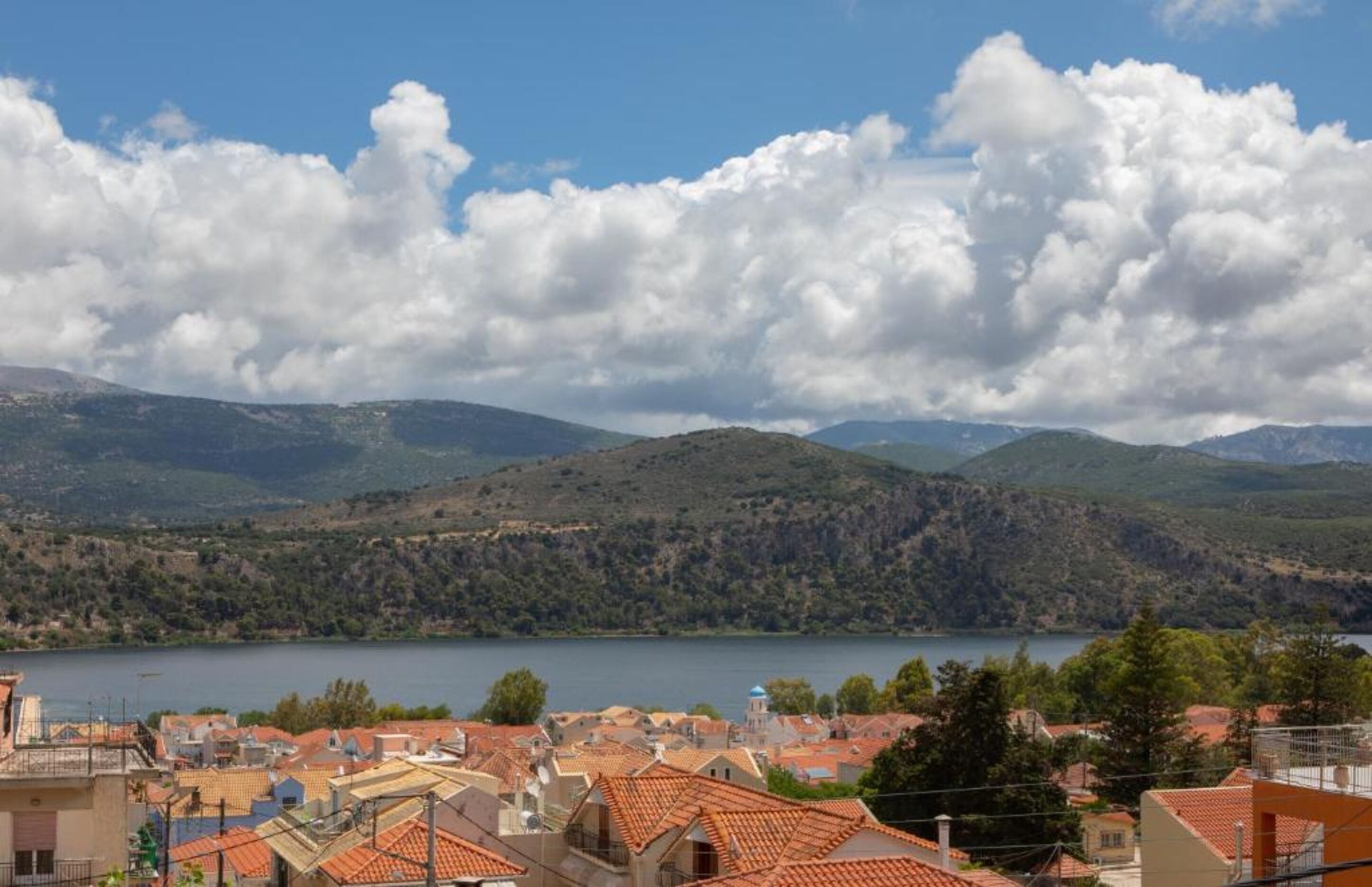 Un pueblo costero con edificios de techos de teja, una masa de agua y colinas ondulantes al fondo.
