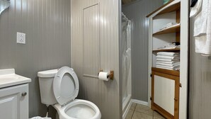 Un baño con inodoro, lavamanos y un armario de madera con toallas.