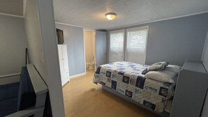 A bedroom with a bed, a desk, and a wardrobe.