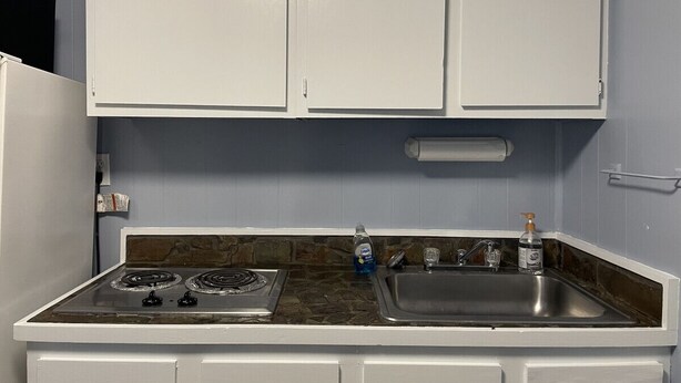 A kitchen with white cabinets, a gas stove, a sink, and a soap dispenser.