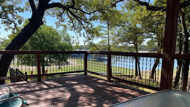 A wooden deck with a view of a lake, surrounded by trees. - Lovely Lake House with Marina and Sunset Views (Pottsboro)