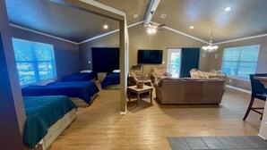 A room with two beds, a sofa, a TV, and a dining area. - Lovely Lake House with Marina and Sunset Views (Pottsboro)