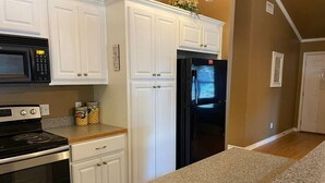 A kitchen with white cabinets, a black refrigerator, a stove, and a microwave. - Lovely Lake House with Marina and Sunset Views (Pottsboro)