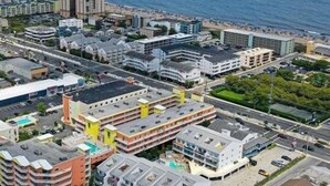 Eine Küstenstadt mit einer Mischung aus Wohn- und Geschäftsgebäuden, darunter mehrstöckige Wohnanlagen und Hotels, mit einem Strand im Hintergrund.