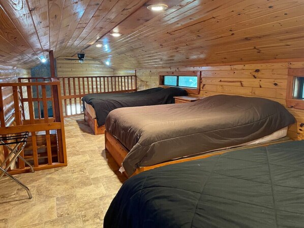 Une cabane avec trois lits en bois, une petite table et une fenêtre.