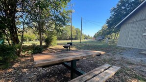 A picnic table in a park with trees and a building in the background.