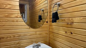 A wooden-paneled bathroom with a white sink and a mirror. - Cozy Cedar Cabin at Mill Creek Marina: Cabin 3 (Pottsboro)