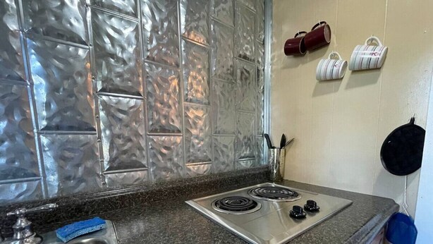 A kitchen with a stainless steel stove, a sink, and a backsplash with a textured pattern.