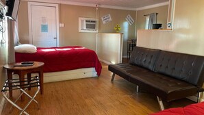 A room with a bed, a sofa, a small table, and a TV.