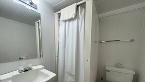 Un baño pequeño con lavamanos, inodoro y cortina de ducha blancos.