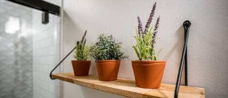 A wooden shelf with three terracotta pots containing plants.
