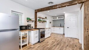 Eine moderne Küche mit weißen Schränken, einem Edelstahlkühlschrank, einer Mikrowelle und einer Holz Arbeitsplatte.
